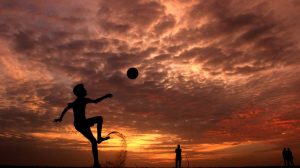 silhouette of a boy playing ball during sunset