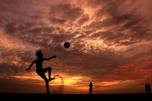 silhouette of a boy playing ball during sunset