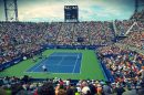 people sitting on bench watching tennis event on field during daytime